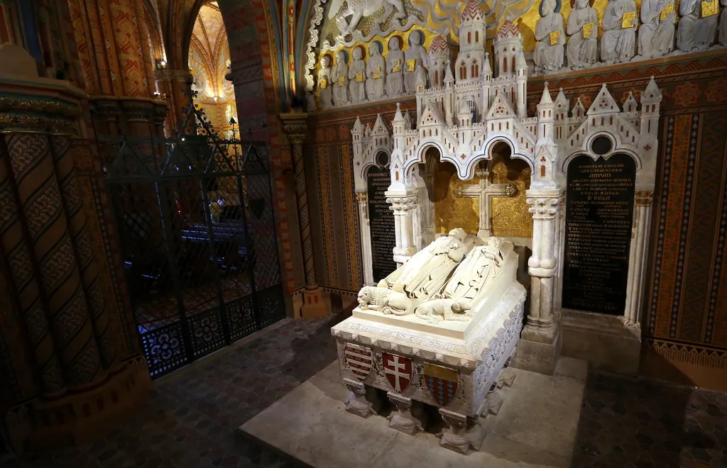 The white stone tomb of Béla III and Agnes of Antioch in a dark side chapel under a pointed Gothic canopy